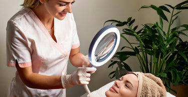 An esthetician in a serene spa setting using a magnifying lamp to examine a client's skin