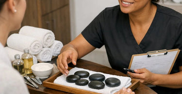 Luxury hot stone massage being applied during a pedicure with smooth black basalt stones at a professional spa.