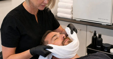 A man enjoys the luxurious warmth of a hot towel finish during a professional grooming session, enhancing relaxation and skin comfort.