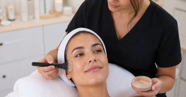 A professional applying mineral based foundation with a brush to a client after a relaxing facial treatment in a spa.