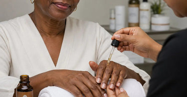 A glass bottle of golden Argan oil resting on a white towel, symbolizing luxurious spa cuticle recovery treatments and professional nail care.