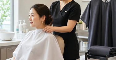 Professional salon capes in use, demonstrating different styles for varied service lengths to protect clients during haircuts and chemical treatments.