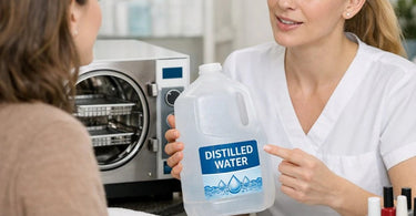 Close up of professional autoclave sterilization machine with a plastic gallon jug of distilled water beside it on a stainless steel counter in a clean spa environment.