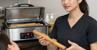 Professional bamboo massage sticks arranged on a heated towel for thermal spa therapy protocols.