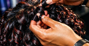 Close-up of a professional hairstylist applying curl defining gel to a client's beautiful, bouncy curls in a salon setting.
