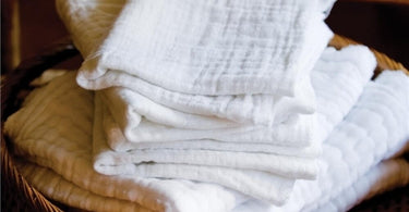 Stack of eight white, soft, textured diaper-style facial cloths from Pure Spa Direct, ideal for professional spa and salon use.