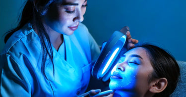 Esthetician examines a client's face using a Wood's Lamp