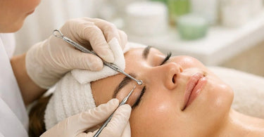 A professional esthetician performing a gentle facial extraction on a client using a metal loop tool, showcasing trauma-free technique.