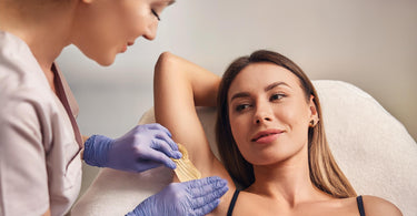 Female client getting armpit wax depilation in a spa clinic