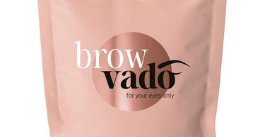 Professional esthetician applying hard wax to shape perfectly arched eyebrows.