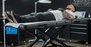 Electric tattoo bed in a modern studio setting, showcasing adjustable features for client comfort and artist efficiency.