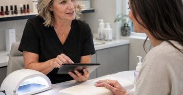 A spa therapist gracefully hands a tablet to a smiling client, illustrating a comfortable and non-pressuring way to ask for a review in a professional beauty setting.