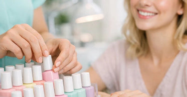 A professional nail technician applying hypoallergenic HEMA-free gel polish to a client's nails in a clean, modern salon setting