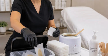 A clean and professional wax strip disposal setup featuring a small trash bin, protective gloves, and a spatula