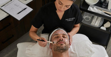 Spa professional performing a signature facial on a male client, focusing on his specific skin concerns.