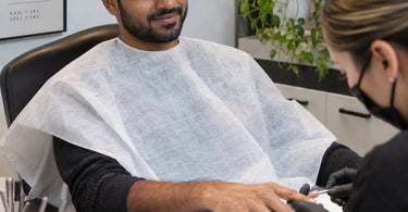 A spa professional hands a client a soft, individually wrapped disposable undergarment to ensure comfort and dignity during their treatment.