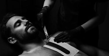 Professional esthetician performing a waxing treatment on a male client in a modern spa setting