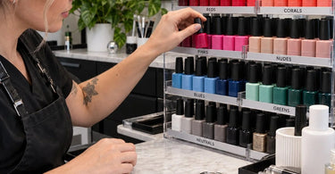 Organized gel polish display by color family showing nudes, pinks, reds, and glitters arranged on a professional salon backbar for fast client color selection