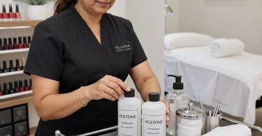 A stack of professional nail polish and acetone bottles on a pristine white work surface, with a clear focus on the acetone bottle, illustrating prevention of surface damage in a nail salon.