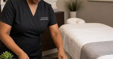 A serene spa treatment room featuring a elegant table with a drawer, a clients purse placed securely on a small stool, and a massage table with warm towels, symbolizing a worry-free experience for clients.