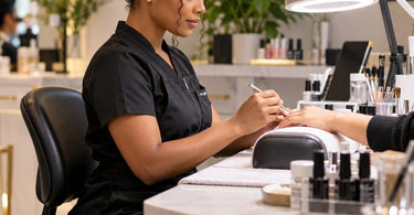 Beauty professional using an ergonomic workstation setup to help prevent neck strain during a detailed salon or spa service