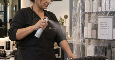 Salon professional arranging a clean retail display of spa products, protecting them from overspray with smart display techniques