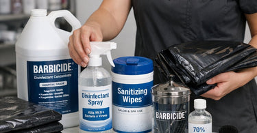 Salon professional sanitizing a plastic combing cape with disinfectant spray on a clean work station