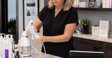 Spa professional cleaning and organizing skincare products and equipment during empty appointment time to maintain a pristine salon environment.