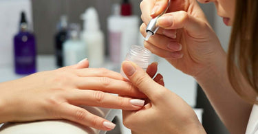 Nail technician applying strengthener to client's nails