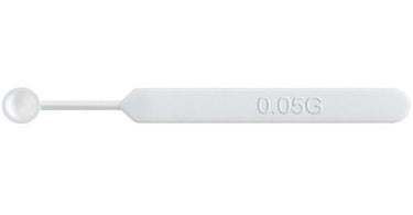 Close-up image of a professional mini sampling spoon on a spa towel, showing its precise size and shape for measuring small amounts of skincare products.