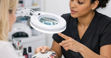 Nail artist using a magnifying lamp for precision nail art detailing on a client at a professional nail station