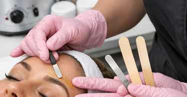 Close up view of professional waxing spatulas in different sizes laid out for precision brow shaping services