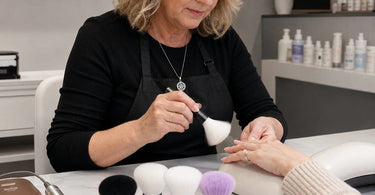 A collection of professional nail duster brushes and an e-file bit displayed on a pink surface, highlighting tools for dust removal.
