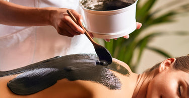 Spa technician applying moor mud to a client during a body treatment