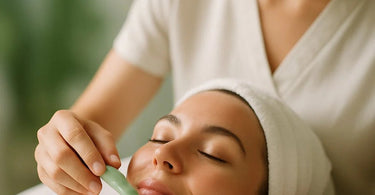 Aesthetician demonstrating proper jade roller technique on a client's face in a spa setting