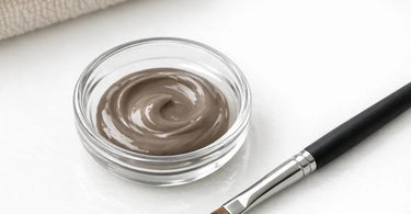 A professional brow artist applying creamy tint to a client's eyebrow for crisp edges without bleeding
