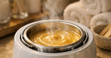 A digital thermometer displaying the accurate temperature of melted wax in a professional wax warmer, with wooden spatulas nearby, symbolizing the key to perfect wax consistency and burn prevention.