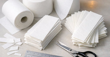 An assortment of different types of professional wax strips including non-woven, woven, and plastic strips, displayed on a light background, illustrating the complete guide to wax strips for salons and spas.