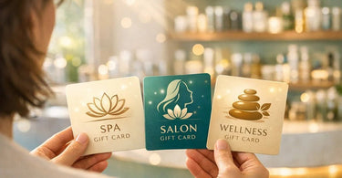A beautifully wrapped spa gift card with luxurious ribbon, sitting beside smooth stones and fresh eucalyptus on a spa towel.