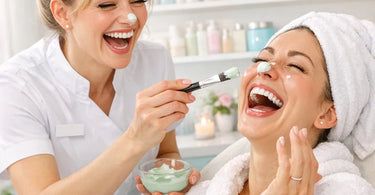 A confident female esthetician smiling while performing a waxing service on a relaxed client in a clean, modern spa treatment room.