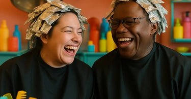 A hairstylist and client sharing a joyful laugh in the salon mirror during a foiling service
