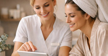 A happy spa professional hands a digital tablet with a waiver form to a smiling client in a modern, relaxing salon waiting area.