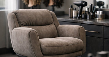 A curl specialist sitting comfortably in an ergonomic salon armchair, working on a client's textured hair, emphasizing posture and support.