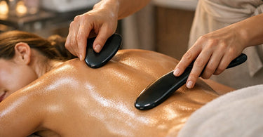 A spa professional performing a gua sha treatment on a client’s back using a smooth stone tool, demonstrating the technique of soft body therapy.