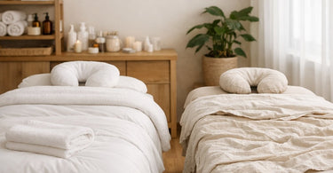 Close-up of luxurious, crisp white massage linens on a professional spa table, showing fine texture and neat folding.