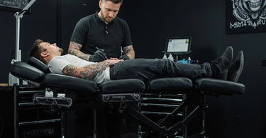 A sleek and modern tattoo client bed in a professional studio setting