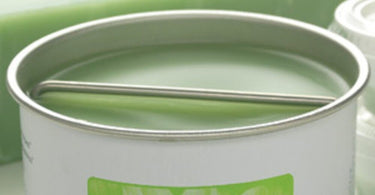 Wax Rest Bar Small by Amber Products sitting next to a professional wax warmer and spatulas on a clean spa table