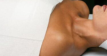 Spa professional preparing a treatment table with a drape sheet