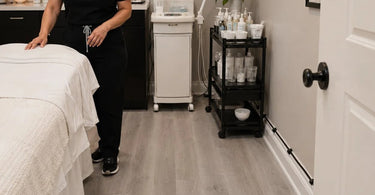 A salon professional carefully managing facial equipment cords to ensure they do not cross the client walkway, illustrating proper spa safety practices.