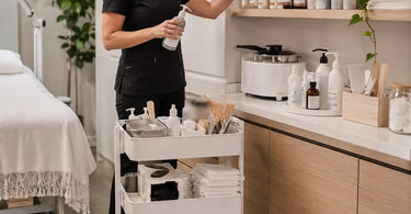 An organized, clean spa treatment room with neatly arranged supplies on shelves and a cart, avoiding clutter on the floor.